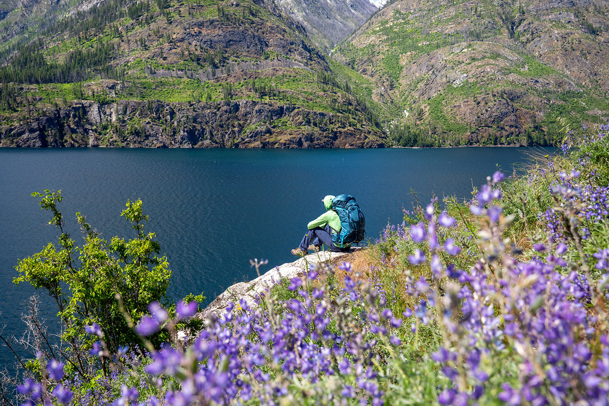 ​​Osprey Atmos AG 65 backpacking back (sitting on rock by lake)